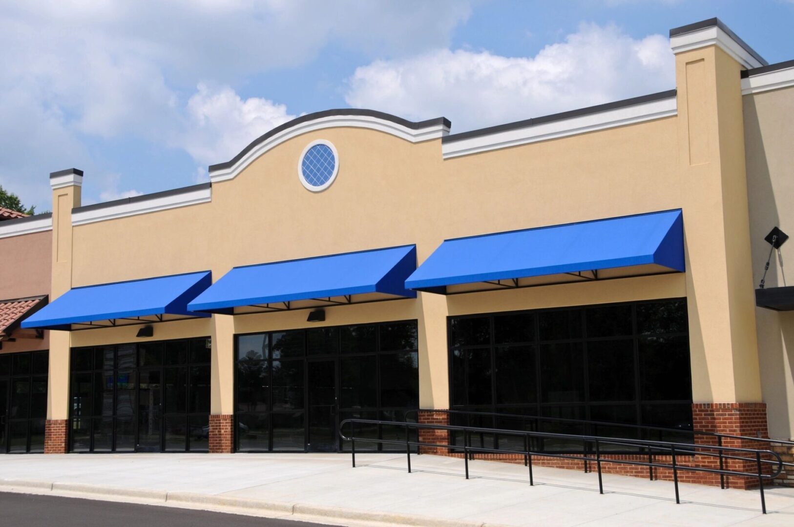 A store front with blue awnings and a sidewalk.